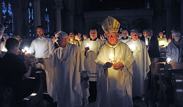 Bishop Richard J. Malone and fellow priests process to the altar, lighting candles, along the way at St. Joseph Cathedral during the Easter Vigil. (Dan Cappellazzo/Staff Photographer)
